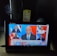 A tablet screen displays a CNN news segment showing results for the 2020 U.S. presidential election with Joe Biden elected president. The broadcast features six separate images of people, including a central anchor and participants in smaller screens. The headline reads 'BREAKING NEWS' and discusses Trump's lack of public acceptance. The setup includes a lit white lamp on the left and a box of crackers sitting behind the tablet.