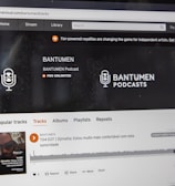 A computer screen displaying a website of an audio streaming service. The website showcases a podcast called BANTUMEN with the description 'Pro Unlimited.' There is a navigation bar with options including Home, Stream, Library, and more. A music wave graphic is visible below, along with a play button, social media interaction options such as re-post, share, and add to playlists. A banner at the top talks about fan-powered royalties, and there is a COVID-19 information widget to the side.