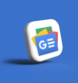 A 3D icon of a stack of cards with the Google News logo, featuring blue, green, yellow, and red colors, set against a solid blue background.